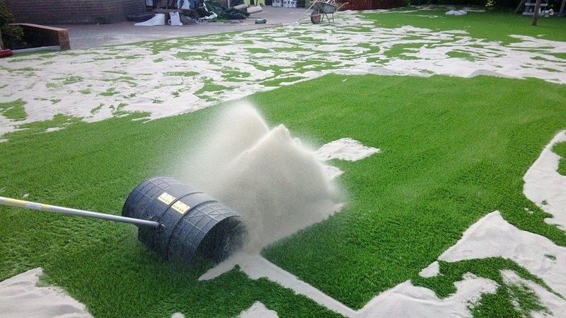 Kunstgras wordt afgespoeld met een sproeier