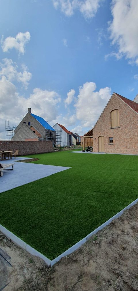 Afgewerkte nieuwbouwtuin in Knokke-Heist met kunstgras tot tegen terras en boordstenen