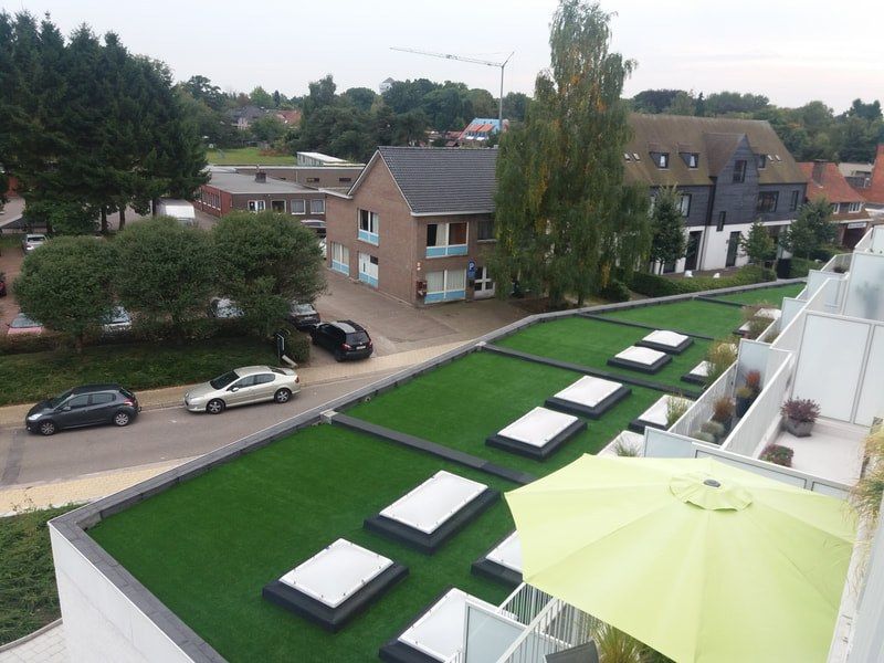 Groot dakterras met kunstgras, parasols en zitmeubilair