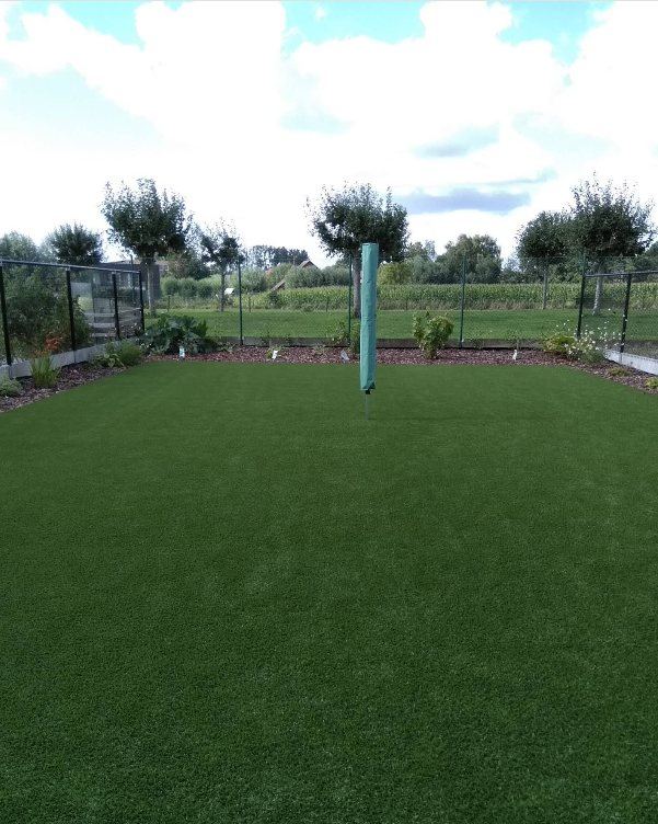 Dezelfde tuin in de zomer, met beplante borders en een droogmolen in het gras